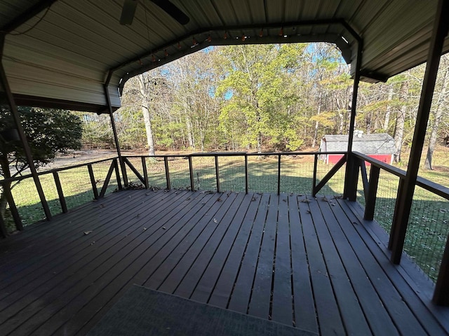 wooden deck with ceiling fan, a storage shed, and a lawn