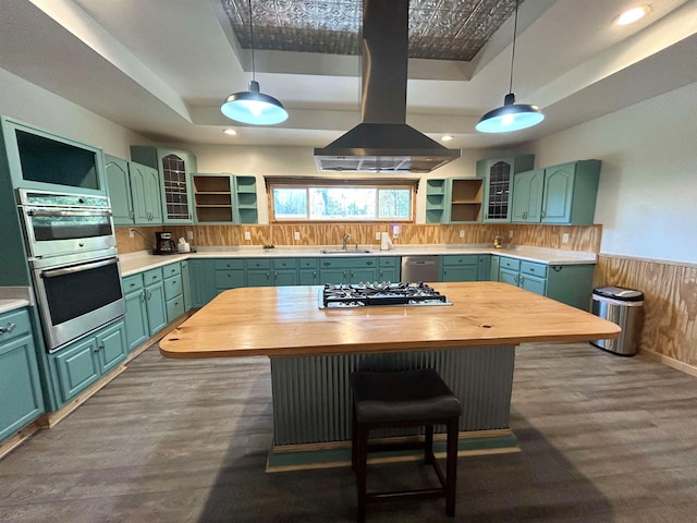 kitchen featuring hanging light fixtures, wooden counters, island range hood, and a center island