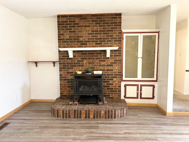 unfurnished living room featuring a wood stove and light hardwood / wood-style floors