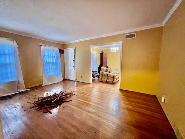 spare room with wood-type flooring, an inviting chandelier, and crown molding