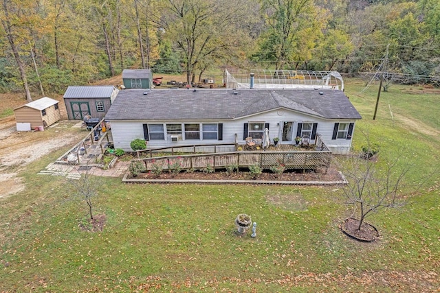 rear view of house featuring a wooden deck, a lawn, and a storage shed