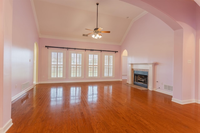 unfurnished living room with hardwood / wood-style floors, high vaulted ceiling, ceiling fan, crown molding, and a fireplace