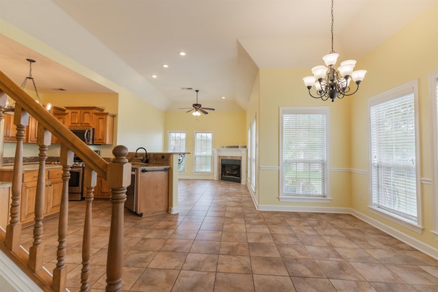 kitchen with stainless steel appliances, decorative light fixtures, light tile patterned floors, vaulted ceiling, and ceiling fan with notable chandelier