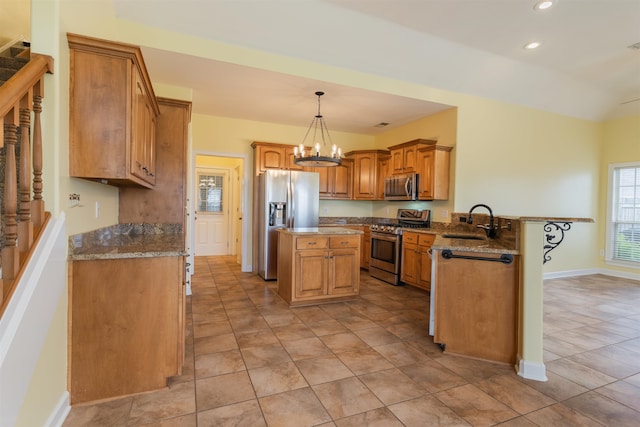 kitchen with a kitchen island, appliances with stainless steel finishes, hanging light fixtures, sink, and dark stone countertops