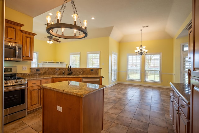 kitchen featuring lofted ceiling, hanging light fixtures, sink, a kitchen island, and appliances with stainless steel finishes