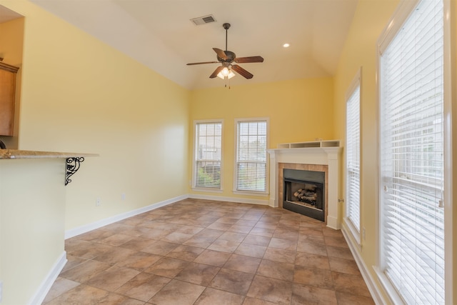 unfurnished living room featuring a tiled fireplace, lofted ceiling, and ceiling fan