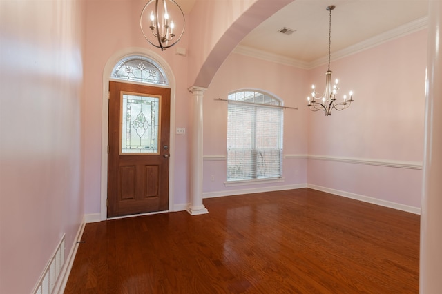 entrance foyer featuring crown molding, ornate columns, dark hardwood / wood-style flooring, and a notable chandelier