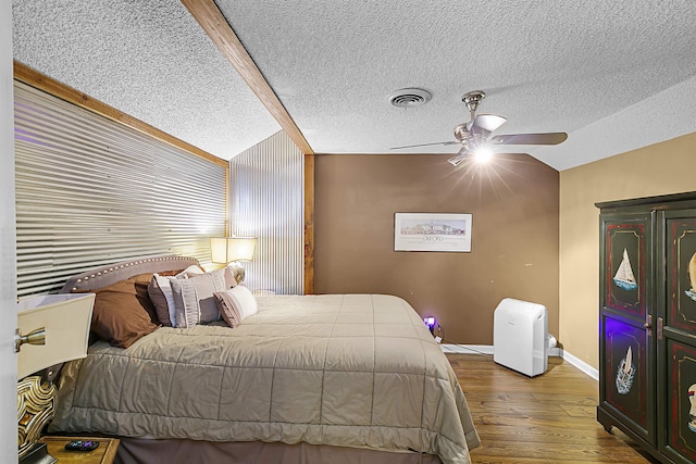 bedroom featuring hardwood / wood-style floors, ceiling fan, a textured ceiling, and vaulted ceiling