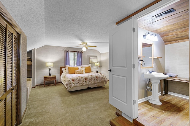 bedroom with a textured ceiling, hardwood / wood-style floors, ceiling fan, and vaulted ceiling