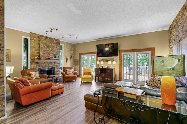 living room featuring hardwood / wood-style floors, a stone fireplace, plenty of natural light, and a textured ceiling