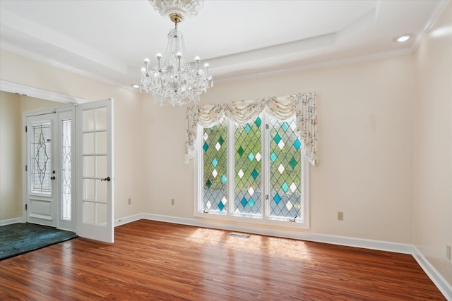 foyer featuring ornamental molding, a tray ceiling, hardwood / wood-style floors, a chandelier, and french doors