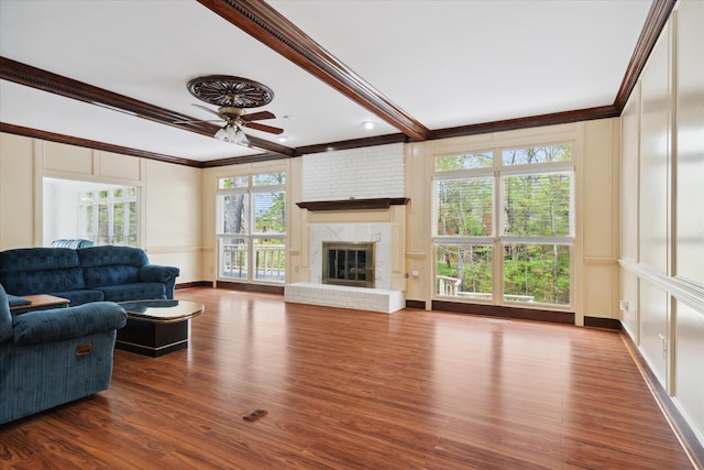 living room featuring a wealth of natural light, crown molding, dark hardwood / wood-style floors, and a fireplace