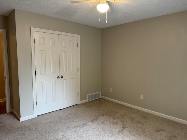 unfurnished bedroom with a textured ceiling, carpet floors, a closet, and ceiling fan