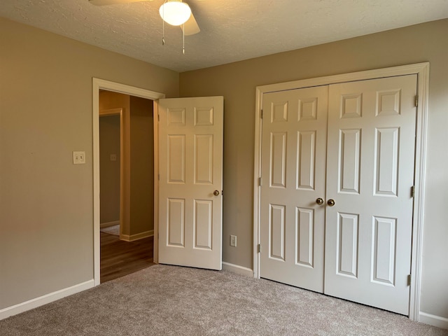 unfurnished bedroom featuring ceiling fan, light colored carpet, a textured ceiling, and a closet