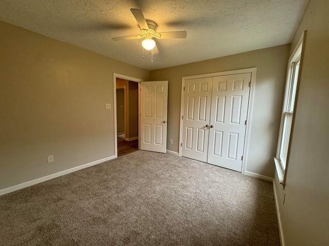 unfurnished bedroom with carpet flooring, ceiling fan, a textured ceiling, and a closet