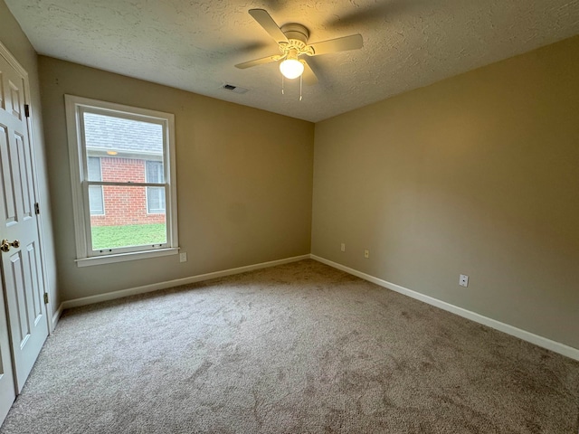 spare room featuring light carpet, a textured ceiling, and ceiling fan