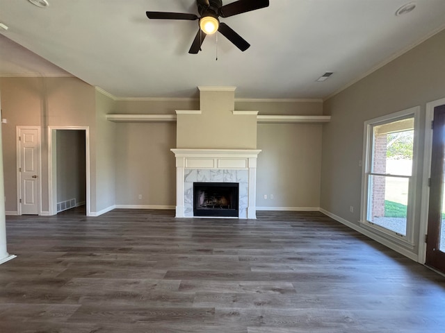 unfurnished living room featuring ceiling fan, dark hardwood / wood-style flooring, a premium fireplace, and ornamental molding