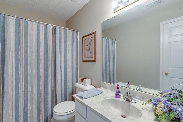 bathroom featuring toilet, vanity, a textured ceiling, and walk in shower