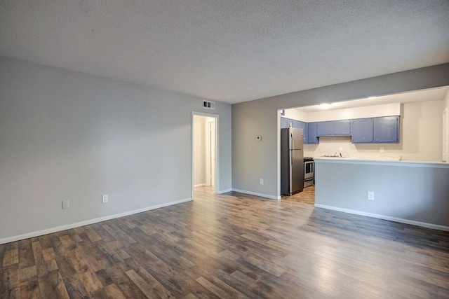 unfurnished living room featuring dark hardwood / wood-style flooring, sink, and a textured ceiling