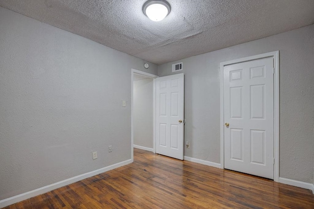 unfurnished bedroom with a textured ceiling and dark hardwood / wood-style floors