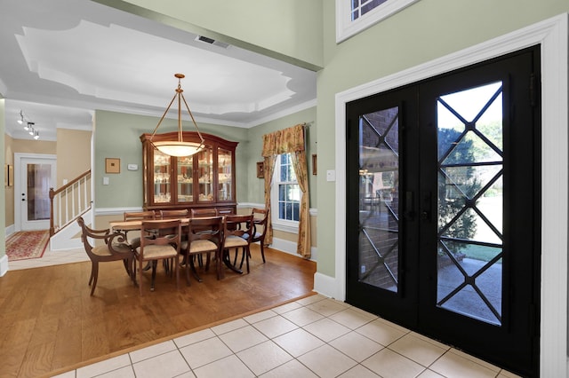 entrance foyer featuring french doors, ornamental molding, light wood-type flooring, and a tray ceiling