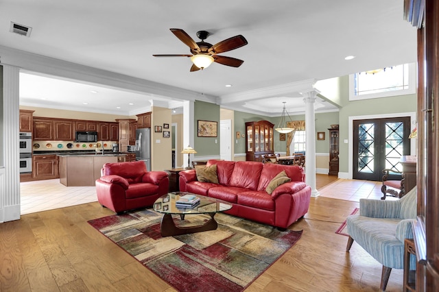 living room featuring sink, decorative columns, ornamental molding, light hardwood / wood-style floors, and french doors