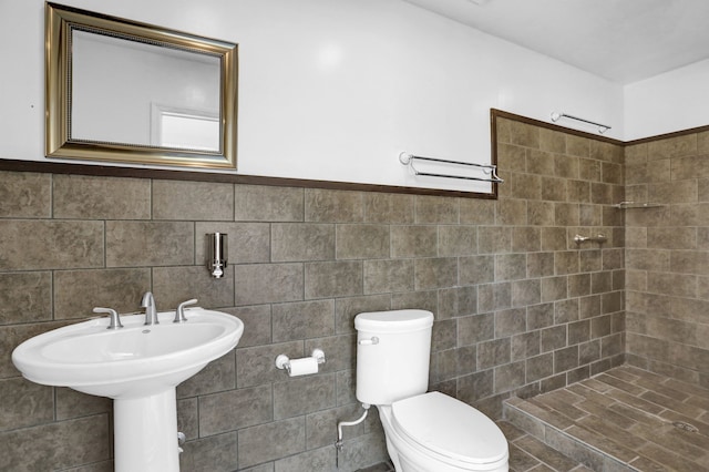 bathroom with toilet, tile walls, and a tile shower