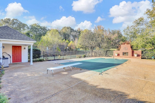 view of pool with exterior fireplace, a diving board, and a patio