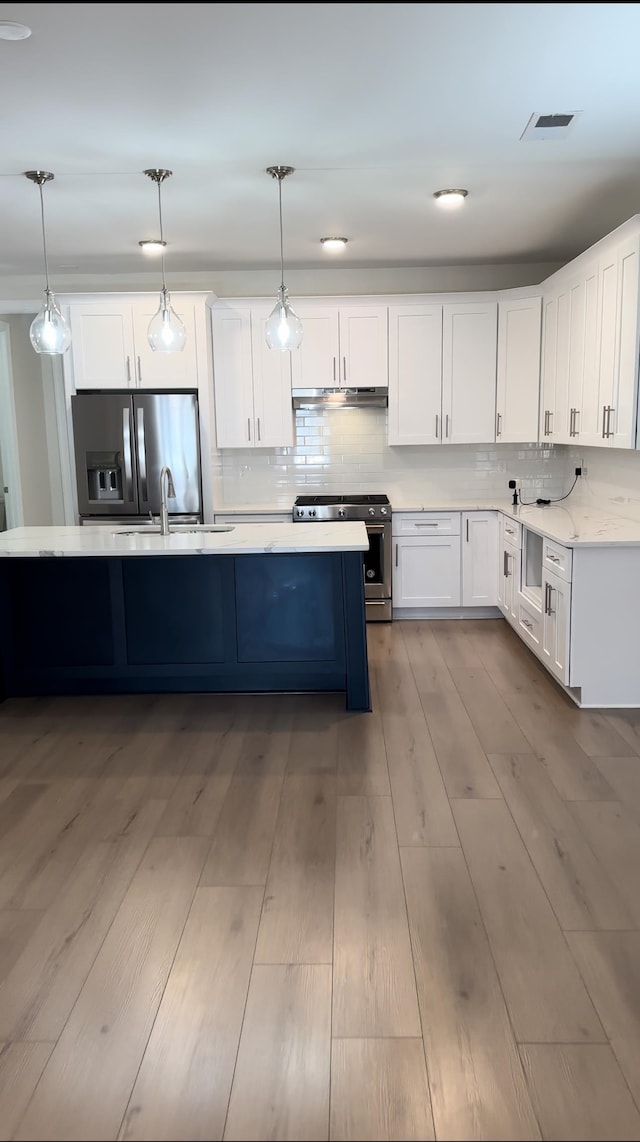 kitchen with white cabinetry, pendant lighting, appliances with stainless steel finishes, and light hardwood / wood-style flooring