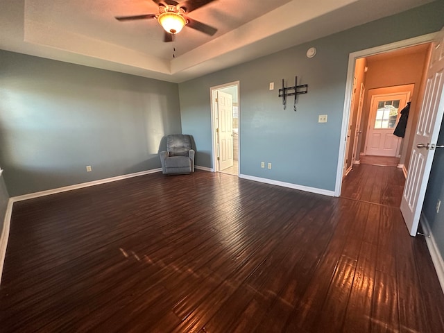 interior space with dark hardwood / wood-style flooring, ceiling fan, and a tray ceiling