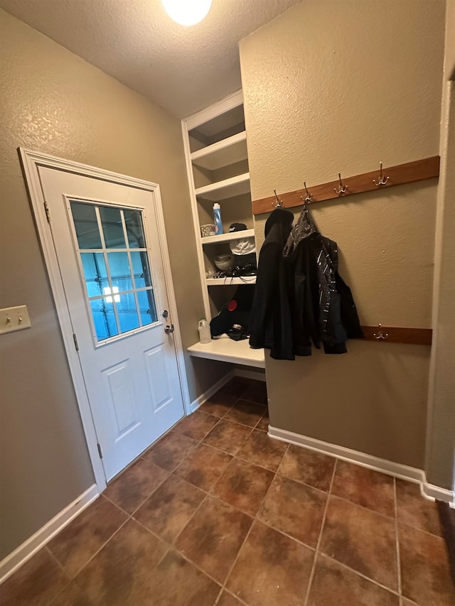 mudroom featuring a textured ceiling and dark tile patterned floors