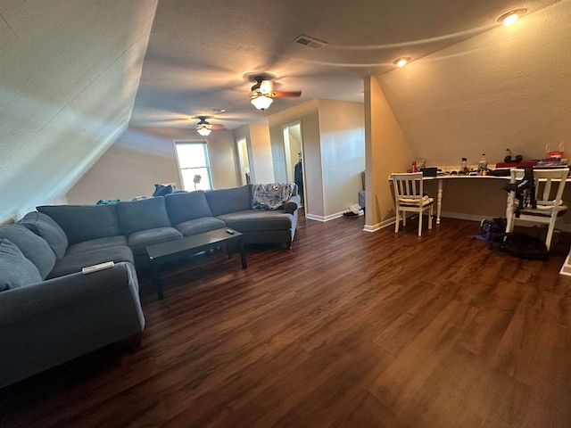 living room with a textured ceiling, dark wood-type flooring, ceiling fan, and vaulted ceiling