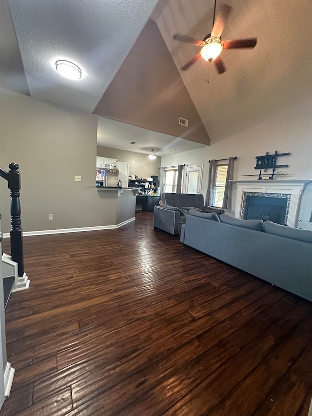 unfurnished living room with ceiling fan, a textured ceiling, high vaulted ceiling, a fireplace, and dark hardwood / wood-style flooring