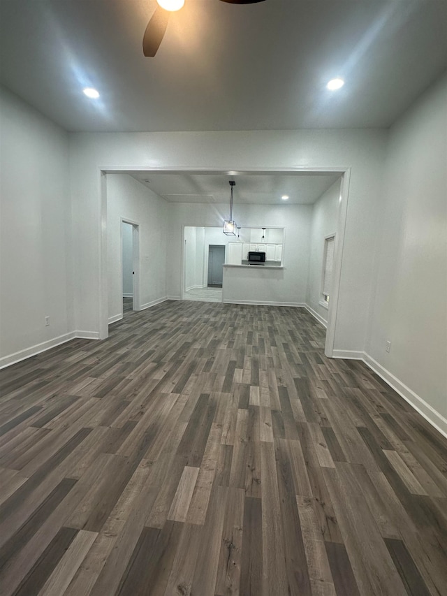 unfurnished living room with ceiling fan and dark wood-type flooring