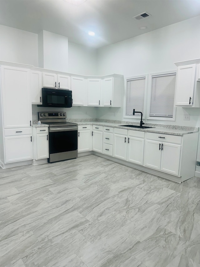 kitchen featuring light stone counters, white cabinetry, stainless steel range with electric stovetop, and sink