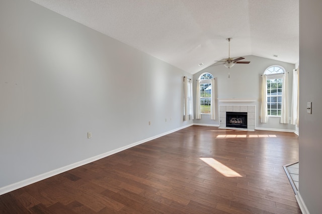 unfurnished living room with a tiled fireplace, dark hardwood / wood-style floors, ceiling fan, and vaulted ceiling