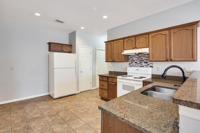 kitchen featuring dark stone counters, a textured ceiling, sink, light tile patterned floors, and white appliances