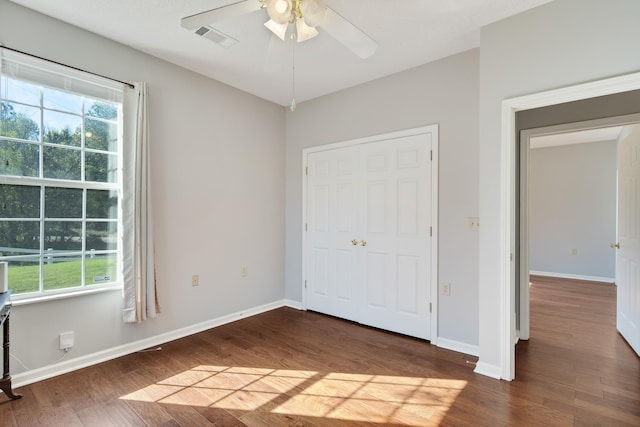 unfurnished bedroom featuring dark wood-type flooring, a closet, and ceiling fan