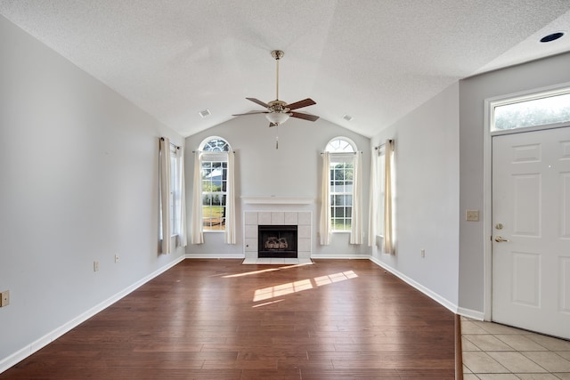 unfurnished living room with light hardwood / wood-style flooring, a textured ceiling, vaulted ceiling, and plenty of natural light