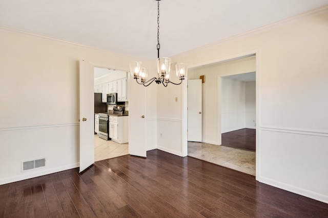 unfurnished dining area featuring a notable chandelier, hardwood / wood-style flooring, and crown molding