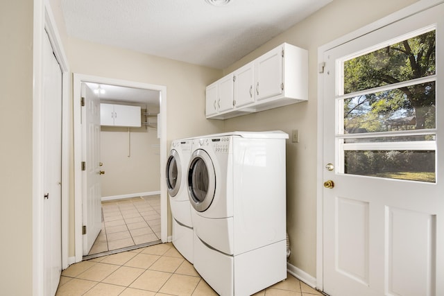 clothes washing area featuring washer and clothes dryer, cabinets, a textured ceiling, and light tile patterned floors