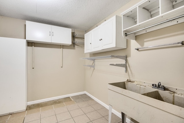 laundry area with a textured ceiling, light tile patterned floors, and sink