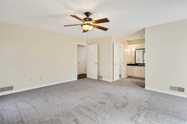 unfurnished room with ceiling fan, a textured ceiling, and light carpet