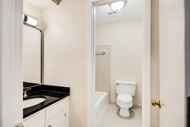 bathroom with toilet, vanity, a textured ceiling, and tile patterned flooring