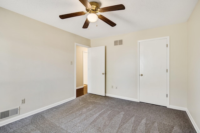 unfurnished bedroom with ceiling fan, a textured ceiling, and dark carpet