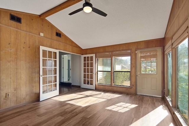 unfurnished sunroom featuring vaulted ceiling with beams, ceiling fan, french doors, and a healthy amount of sunlight