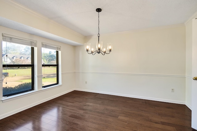 spare room featuring ornamental molding, dark wood-type flooring, a textured ceiling, and an inviting chandelier