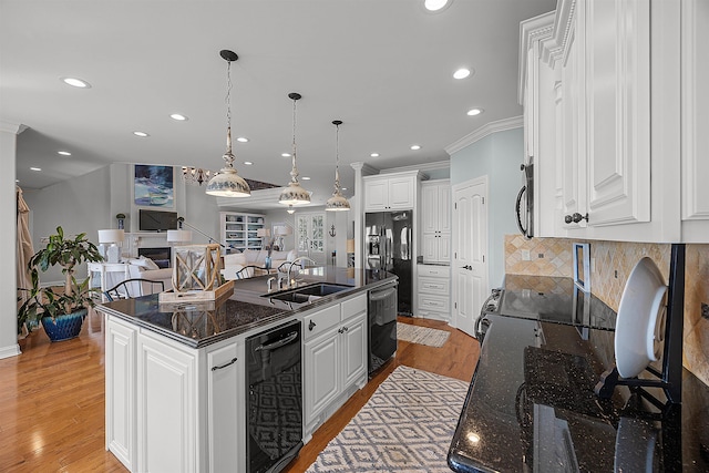 kitchen with white cabinets, a center island with sink, sink, and black appliances