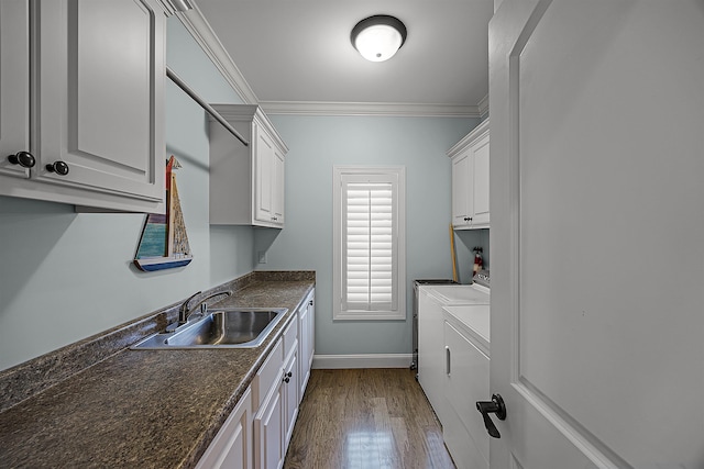 laundry area with wood-type flooring, cabinets, sink, ornamental molding, and washer and dryer