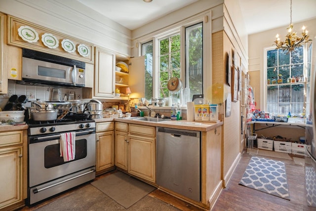 kitchen featuring stainless steel appliances, pendant lighting, sink, dark wood-type flooring, and a chandelier